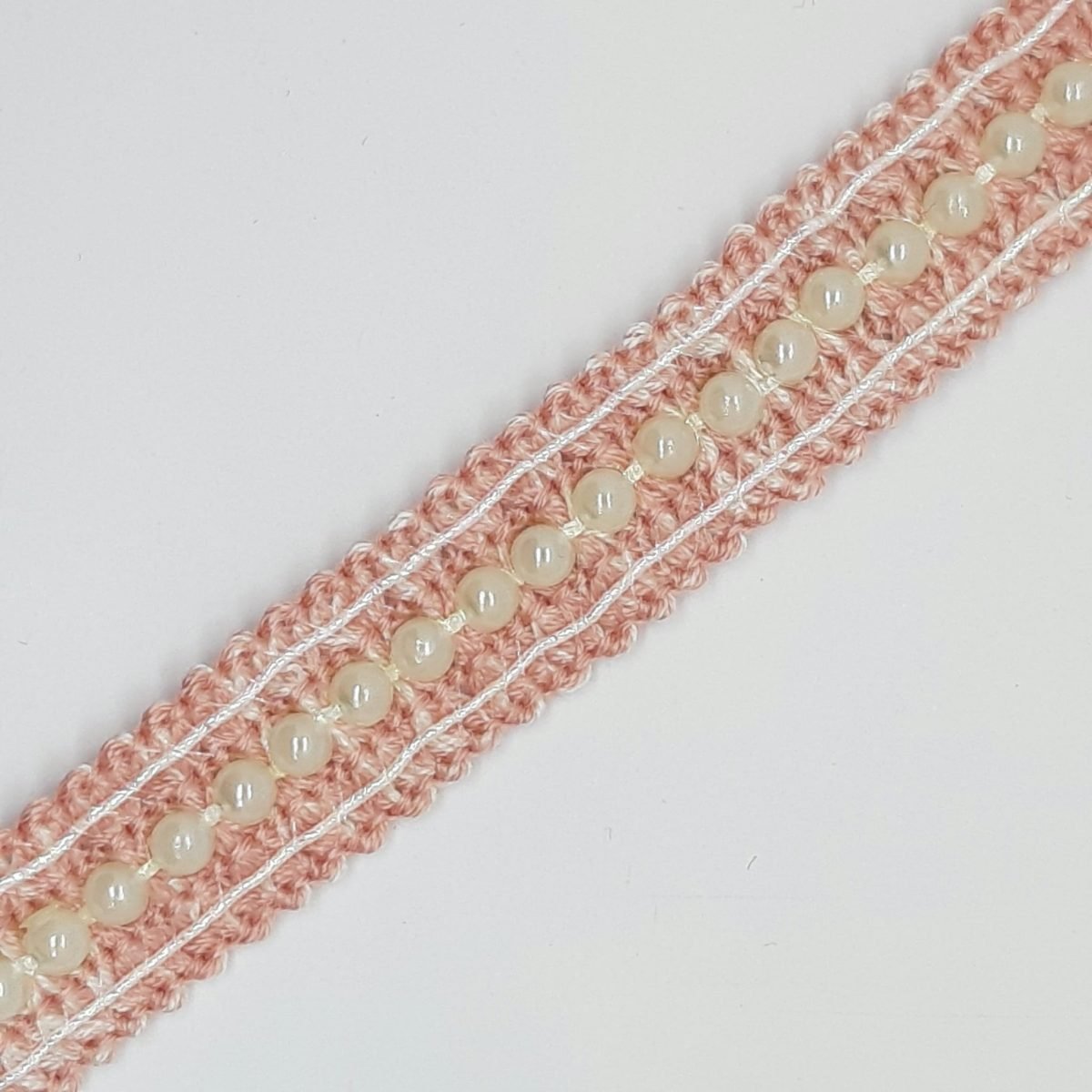 Pasamanería rosa con perlas decorativas.