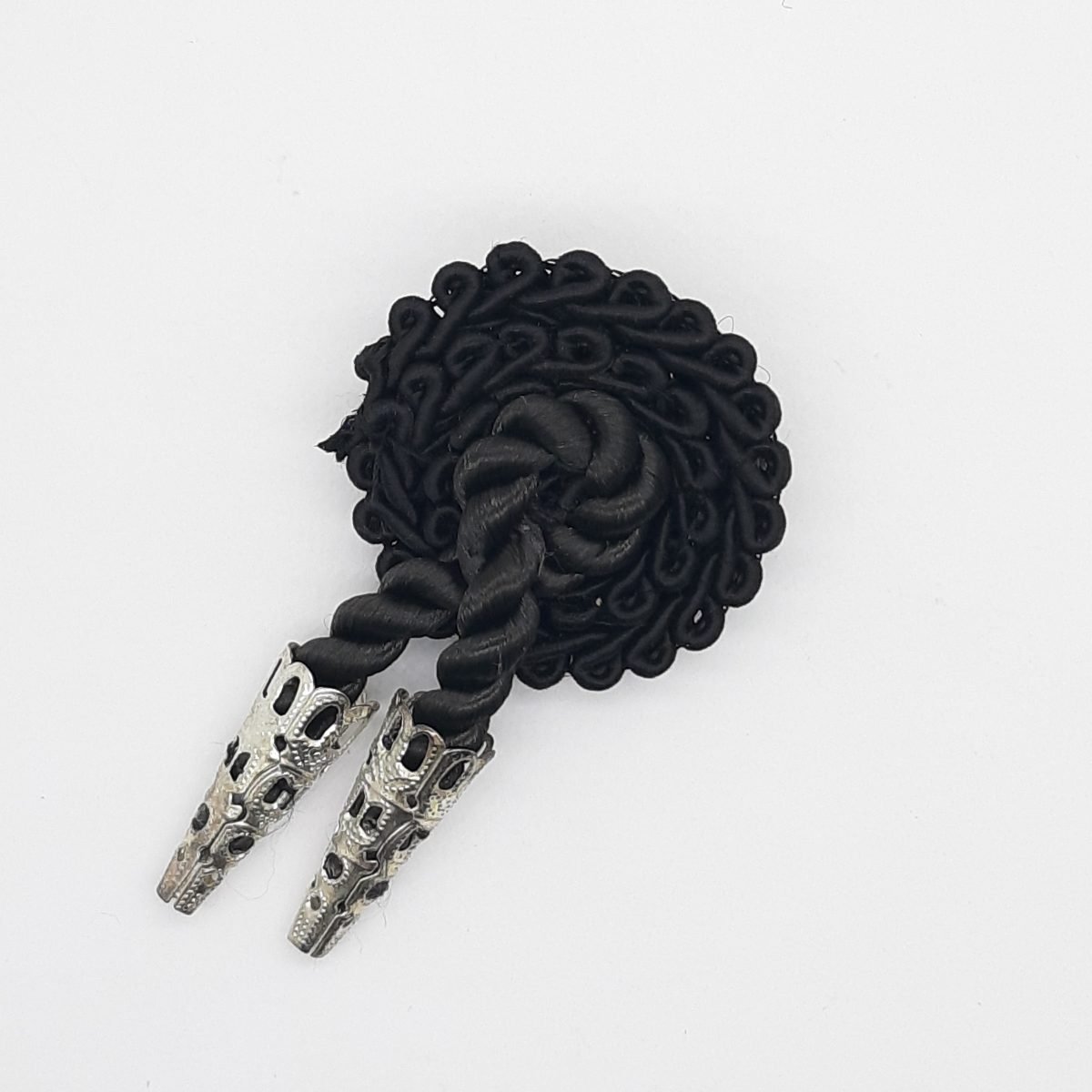 Alamar de pasamanería con cairel negro de seda y dos cabuzones plateados.